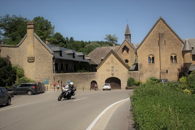 Vallonia in moto: esterno dell'Abbazia di Orval, sullo sfondo le persone col carrello che caricano le birre in macchina.